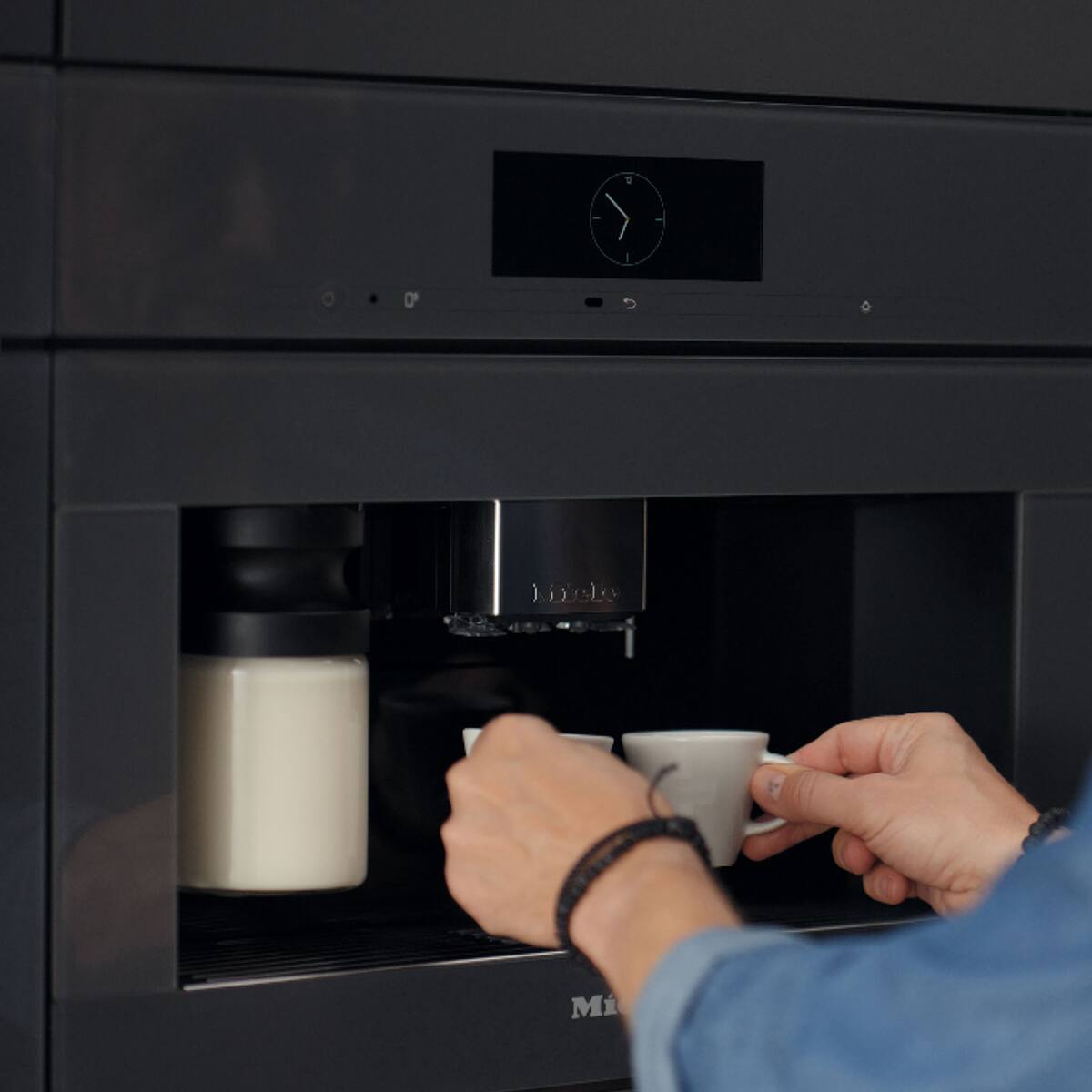 A person using her mobile phone to control the Miele coffee machine